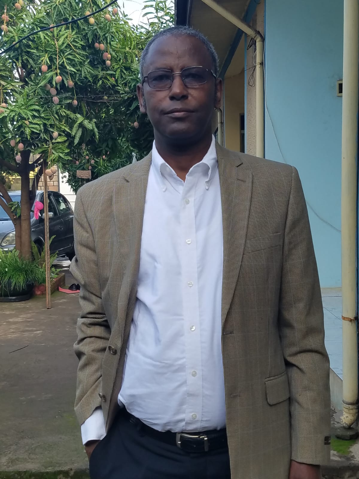 Professor Meareg Amare in the courtyard of his home, wearing new clothes from his sons, with his wife.