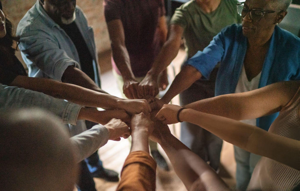 A diverse circle of community members joining hands together