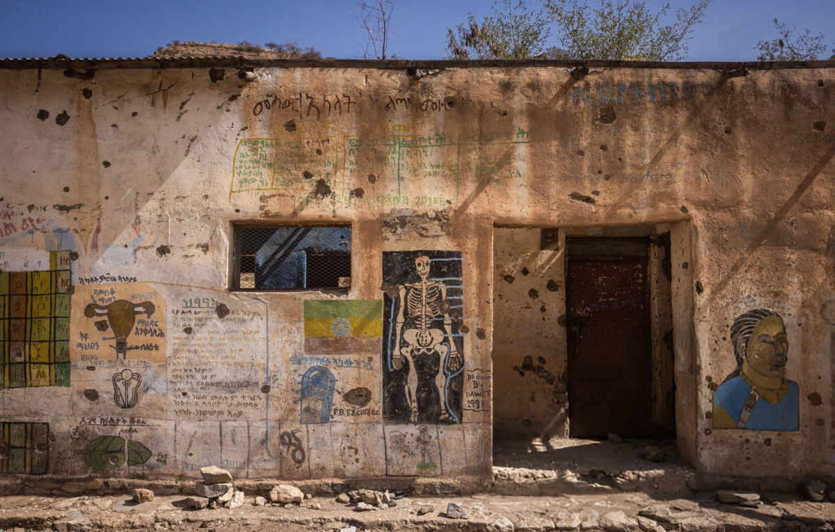 A war-damaged school building in Tigray, its walls scarred by bullet holes and covered in educational murals